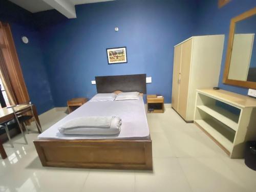 1 dormitorio con cama y pared azul en Chief Guest House, en Āīzawl