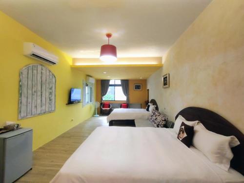 a hotel room with two beds and a tv at Mamamia Homestay in Hengchun