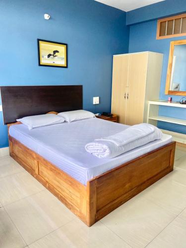 a large bed in a bedroom with a blue wall at Chief Guest House in Āīzawl