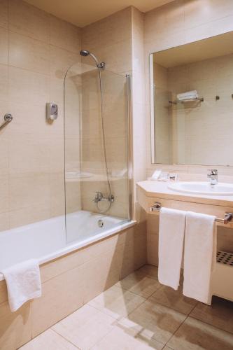 a bathroom with a shower and a tub and a sink at Hotel Arha Mar Comillas in Comillas