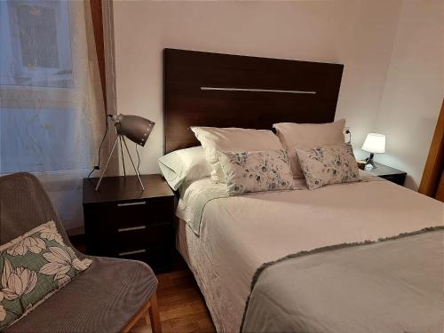 a bedroom with a bed and a lamp and a chair at Apartamento ria de Viveiro in Viveiro