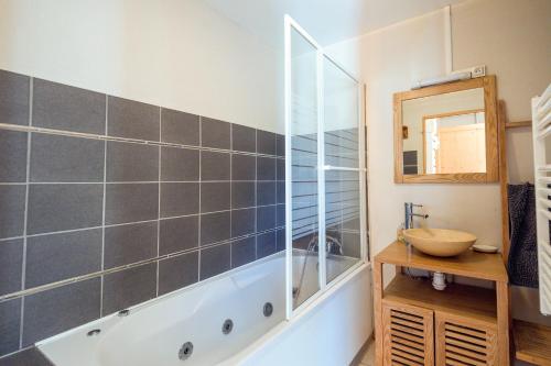 bagno con vasca, lavandino e specchio di La Forêt de Ventron a Ventron