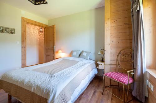 1 dormitorio con 1 cama blanca y 1 silla roja en La Forêt de Ventron en Ventron