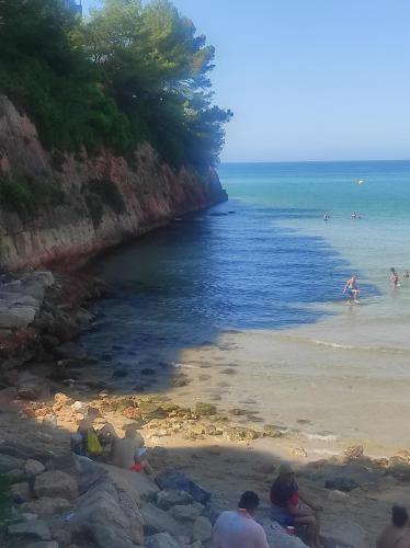a group of people sitting on a beach near the ocean at Paradise Village Port Aventuras in Salou