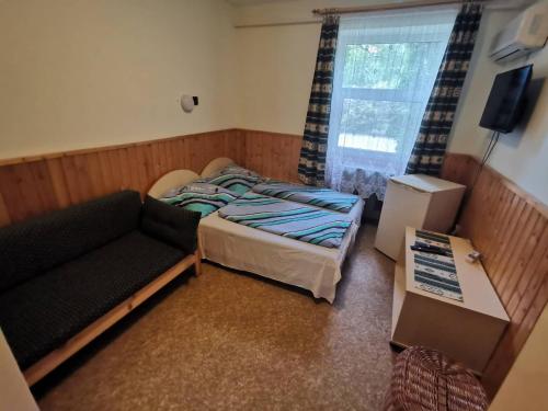 mała sypialnia z łóżkiem i kanapą w obiekcie Platán üdülő w mieście Balatonlelle