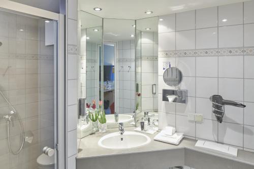 a bathroom with a sink and a mirror at Parkhotel Weiskirchen in Weiskirchen