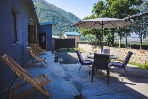 a patio with a table and chairs and an umbrella at Apartments Gio-Nika in Stepantsminda