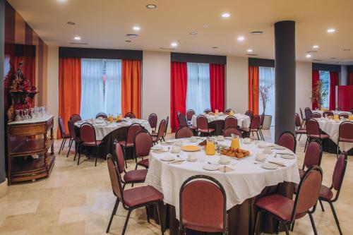 a conference room with tables and chairs with food on them at Hotel Arha Mar Comillas in Comillas