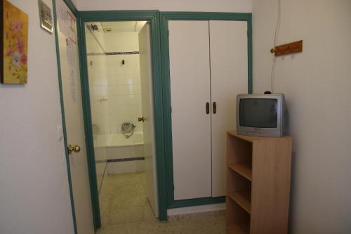 a room with a television and a door to a bathroom at Pensión Campomar in Cartaya