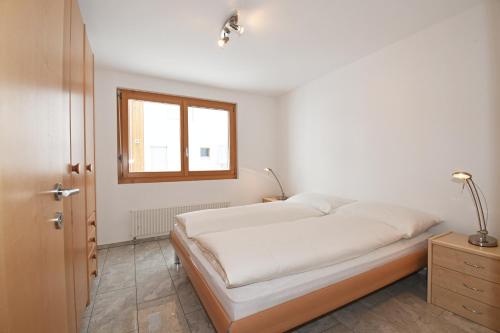 ein weißes Schlafzimmer mit einem Bett und einem Fenster in der Unterkunft Sophia 1. Stock West in Riederalp