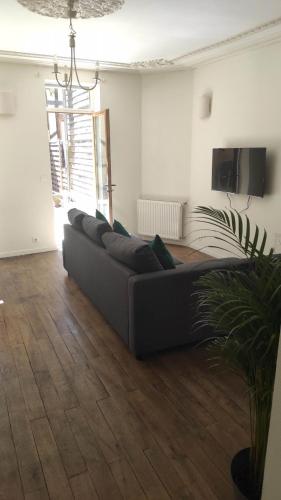 a black couch in a living room with a wooden floor at AUBIGNY SUR NERE in Aubigny-sur-Nère