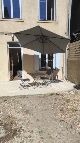 zwei Stühle und ein Regenschirm vor einem Gebäude in der Unterkunft AUBIGNY SUR NERE in Aubigny-sur-Nère