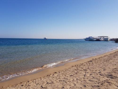 einen Sandstrand mit einem Boot im Wasser in der Unterkunft Apartment Place of Dreams near the sea RedSeaLine in Hurghada