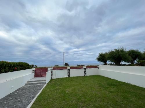 a white fence with a grassy yard at Lila Beach Villa in Ponta Delgada