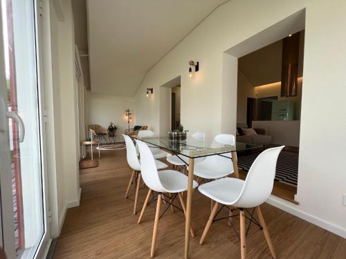 a dining room with a glass table and white chairs at Lila Beach Villa in Ponta Delgada