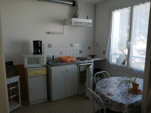 a small kitchen with a table and a sink and a microwave at Hotel la coursive in La Cotinière