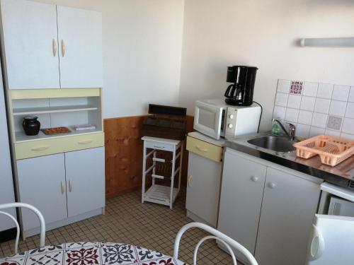 eine kleine Küche mit einer Spüle und einer Mikrowelle in der Unterkunft Hotel la coursive in La Cotinière
