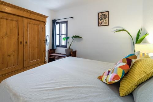 a bedroom with a large white bed with yellow pillows at Town house with roof terrace and plunge pool in Alcaucín