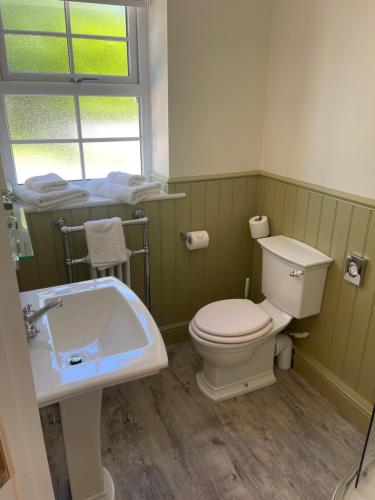 a bathroom with a toilet and a sink and a window at The Black Bull Inn in Lowick
