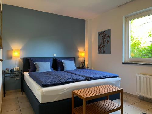 Un dormitorio con una cama con sábanas azules y una ventana. en Reis - feine Weine "Am Weingut", en Briedel