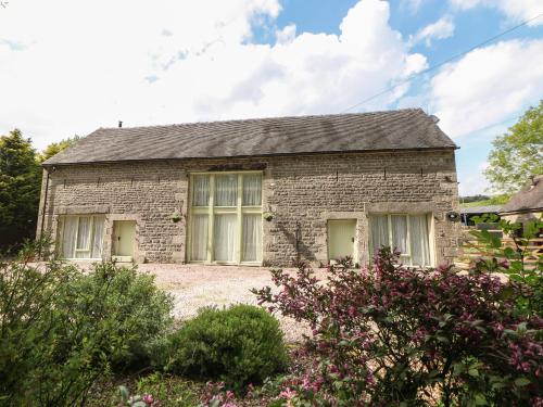 a stone house with two windows in a garden at Ford Coach House Cottage in Leek