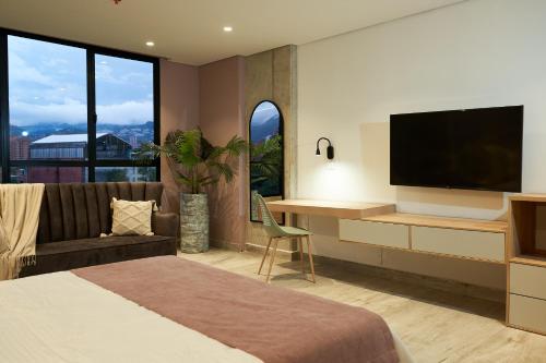 a bedroom with a bed and a desk with a television at Eutopiq Hotel in Medellín
