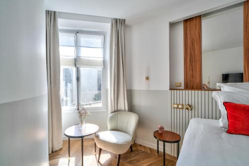 ein Schlafzimmer mit einem Bett, einem Stuhl und einem Fenster in der Unterkunft Sompteux appartement proche de L'Opéra in Paris