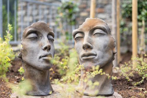 two statues of three heads in a garden at Luxury Apart Sailers including Premium Summercard in Sankt Anton am Arlberg