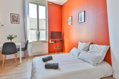 1 dormitorio con pared de color naranja, cama y escritorio en TERRA COTTA #Hypercentre #Charente #Parking, en Cognac