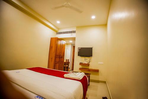 a bedroom with a bed and a flat screen tv at KKM International in Kuzhittura