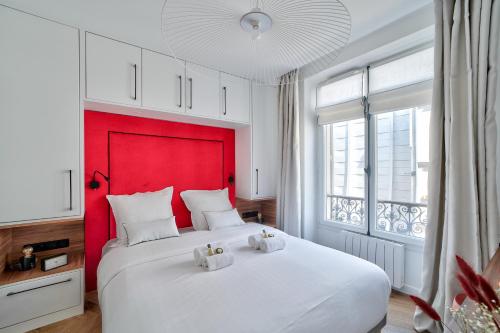 sypialnia z dużym białym łóżkiem z czerwonym zagłówkiem w obiekcie Sublime appartement au coeur de Paris w Paryżu