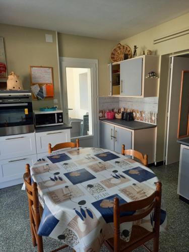 eine Küche mit einem Tisch mit einer Tischdecke darauf in der Unterkunft Maison proche la tremblade et de ronce les bains in Étaules