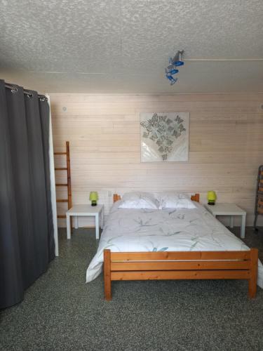 ein Schlafzimmer mit einem großen Bett mit zwei Tischen in der Unterkunft Maison proche la tremblade et de ronce les bains in Étaules