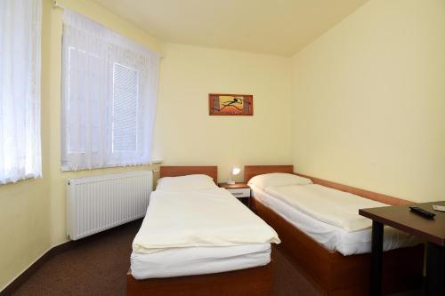 a room with two beds and a desk and a window at Hotel U Jezírka in Liberec