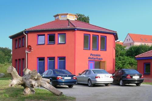 un bâtiment avec des voitures garées dans un parking dans l'établissement Pension Sassnitz Atelierhaus, à Sassnitz