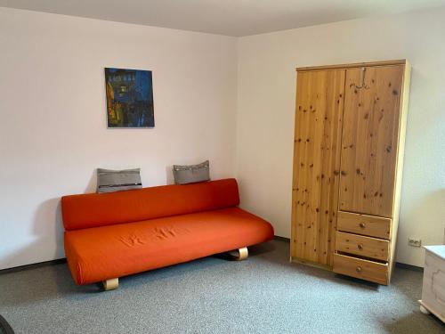 Pension Sassnitz Atelierhaus في ساسنيتز: مقعد برتقالي في غرفة مع خزانة