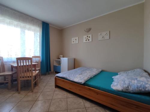 a bedroom with a bed and a table and a chair at Willa Zacisze Sianożęty in Sianozety
