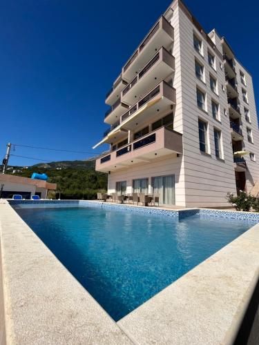 a building with a swimming pool in front of a building at Lux Hotel M in Dobra Voda