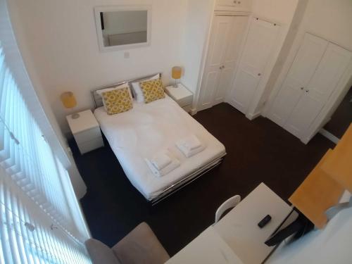 - une petite chambre avec un lit blanc et des oreillers dans l'établissement Kensington Gardens, à Londres