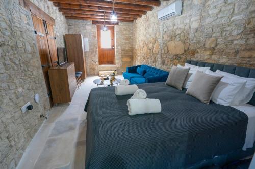 a bedroom with a large bed and a blue couch at Eidyllio Luxury Suites Omodos in Omodos
