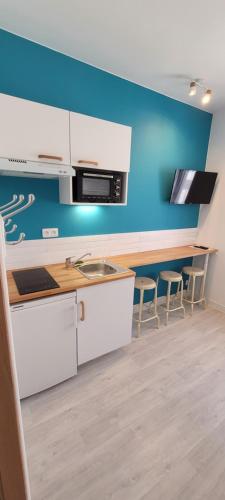 une cuisine avec des armoires blanches et un mur bleu dans l'établissement Studio BLEU - à 100 m de la plage de Berck, à Berck-sur-Mer