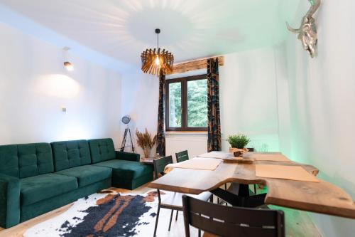 sala de estar con sofá verde y mesa de madera en Bieszczady Guest House en Czarna