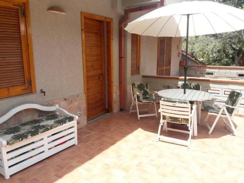 een patio met een tafel en een parasol bij Appartamento Airone in Piraino
