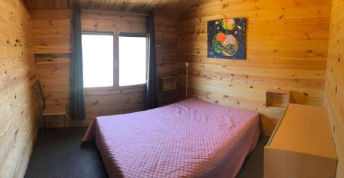 a small room with a bed in a wooden cabin at Chalet 35m2 Domaine du vieux chêne in Bergerac