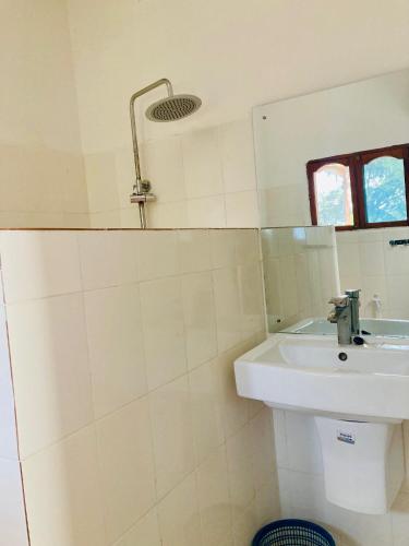 a white bathroom with a sink and a mirror at Kaure Sand Beach Lodge in Uroa