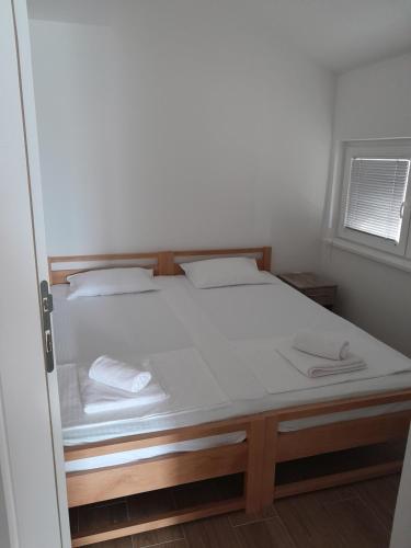 a bedroom with a bed with white sheets and a window at Spa Koncept-Apartmani in Veliko Gradište