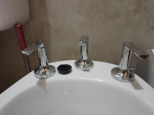 un lavandino bianco con due rubinetti sopra di Habitación amplia con baño privado - sin aire acondicionado con ventiladores - Serena Alojamientos a Villa Constitución