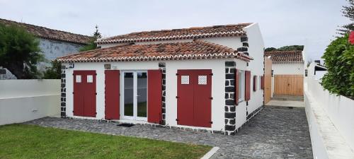 a small house with red doors in a yard at Lila Beach Villa in Ponta Delgada