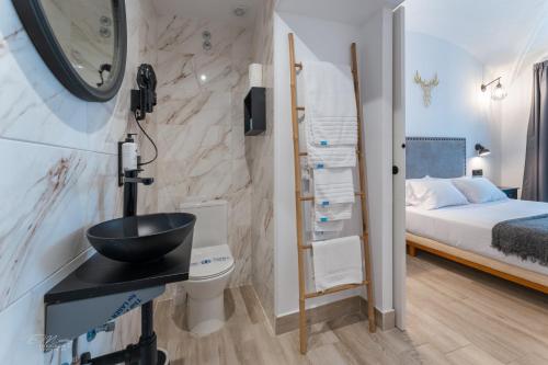 a bathroom with a sink and a bedroom with a bed at La Posada del Teatro H Boutique Aparcamiento gratuito in Merida