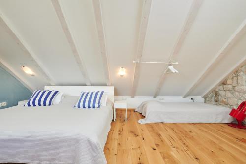 a bedroom with two beds and a stone wall at Domus Maritima in Trogir